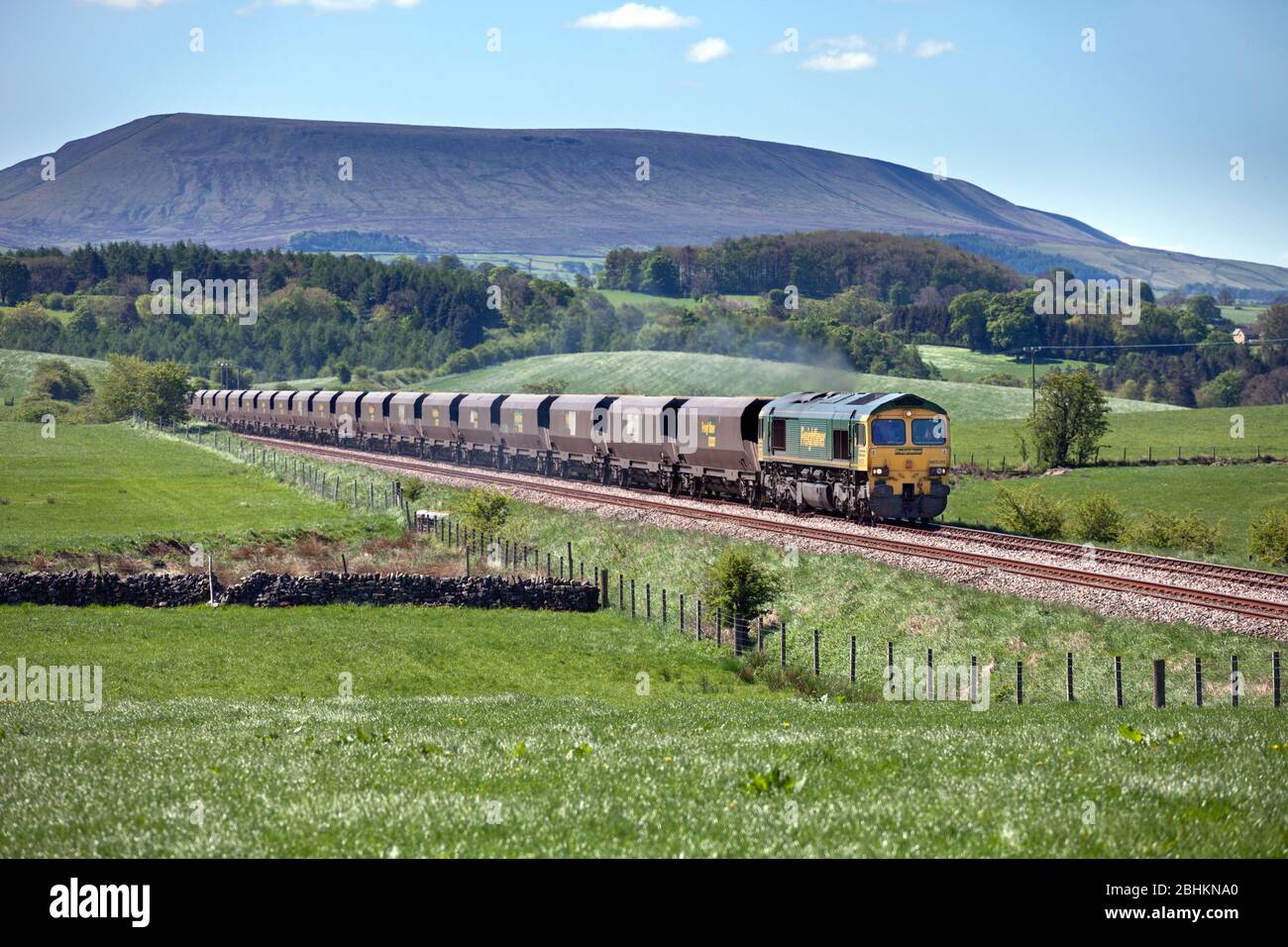 Freightliner classe 66 locomotiva 66520 trasporto di un treno merci a carbone 'merry go round' sulla ferrovia Blackburn a Hellifield, Pendle Hill è dietro. Foto Stock