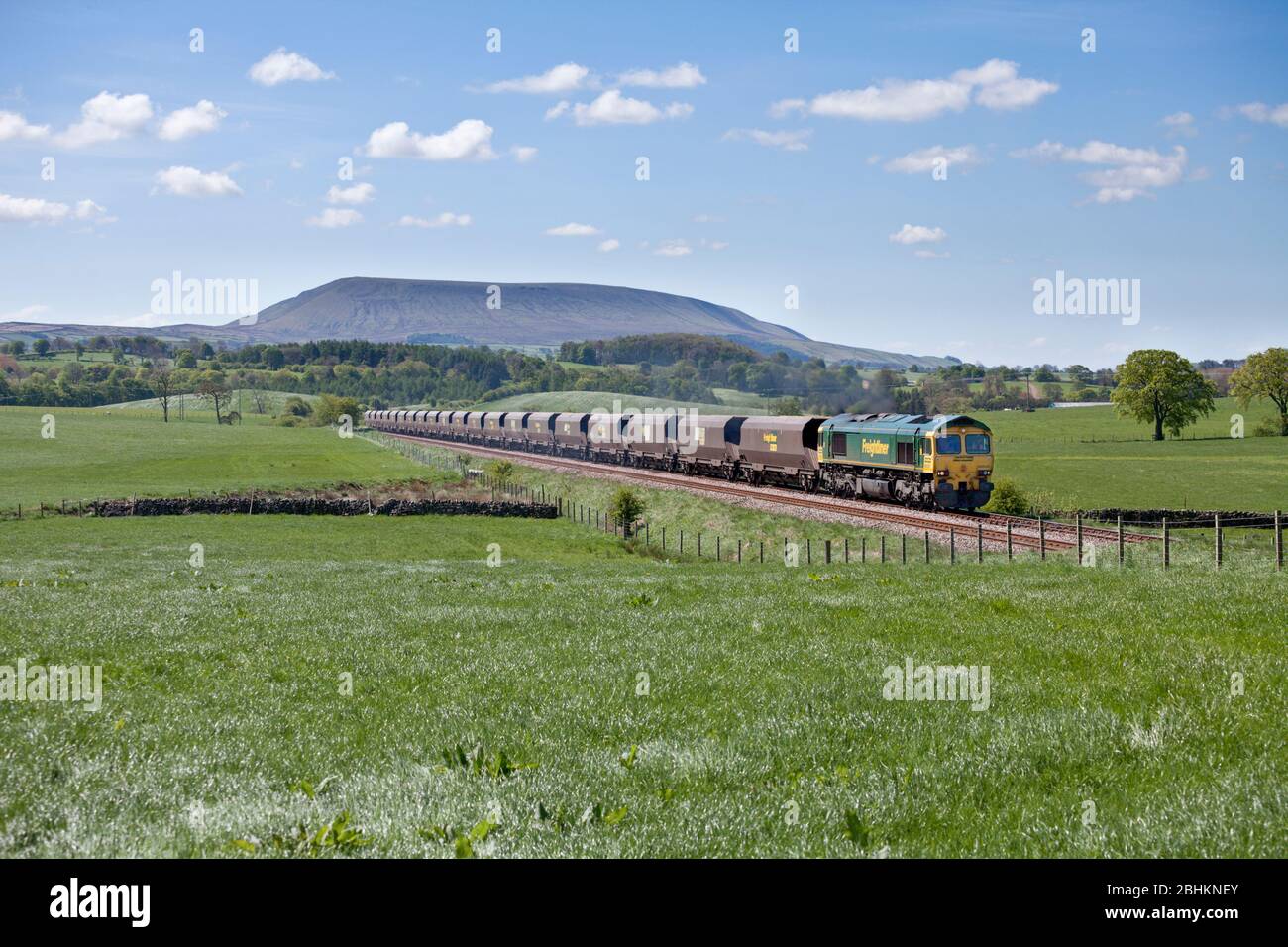 Freightliner classe 66 locomotiva 66520 trasporto di un treno merci a carbone 'merry go round' sulla ferrovia Blackburn a Hellifield, Pendle Hill è dietro. Foto Stock