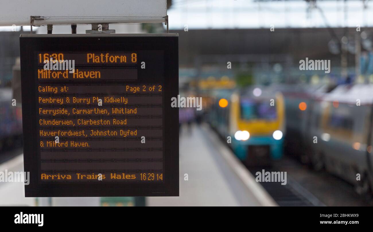 Informazioni sulla partenza del treno: Imbarco alla stazione di Manchester Piccadilly con un treno sullo sfondo Foto Stock