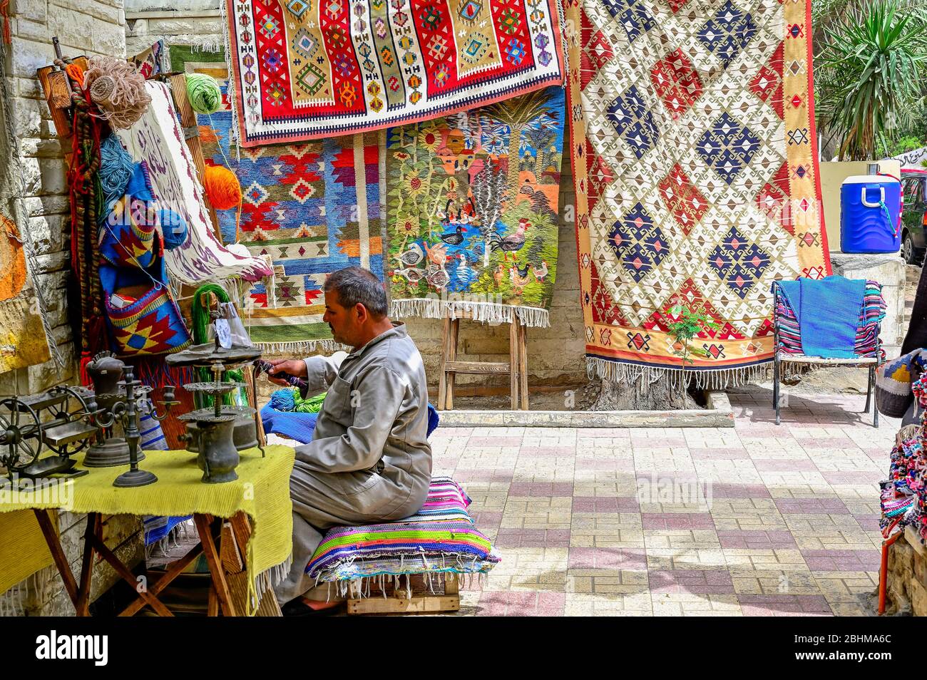 Artigiano che lavora nel suo laboratorio all'aperto sulla strada 9, Maadi, tessitura di un tappeto utilizzando la macchina di tessitura tradizionale Foto Stock