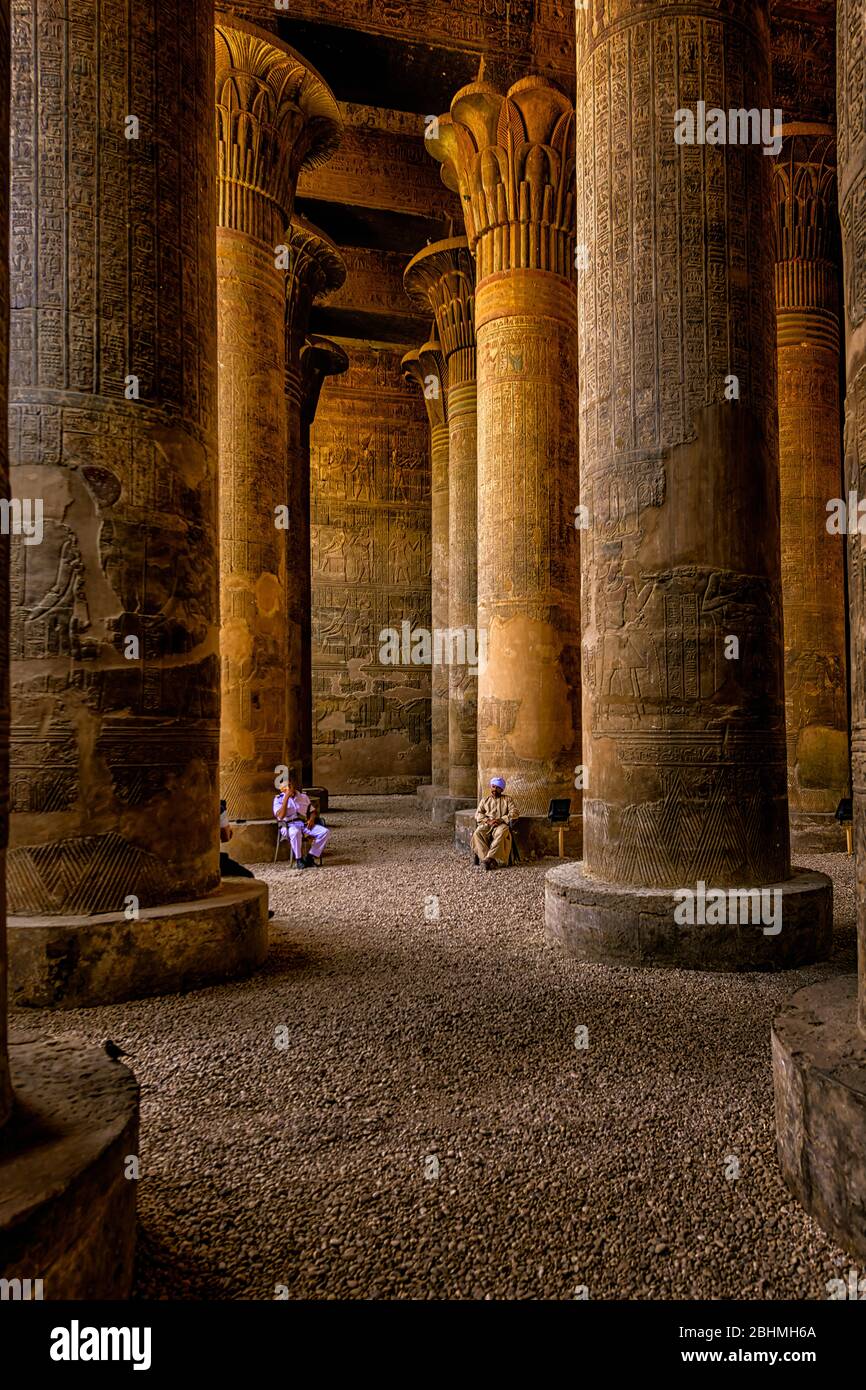 Le guardie di sicurezza si siedono alla base delle enormi colonne della Sala dell'Ipotstile nel Tempio di Esna Foto Stock