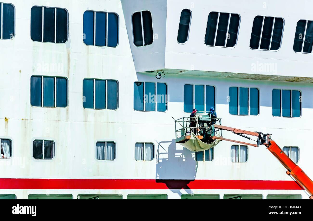I lavoratori che indossano maschere riverniciscono il lato della nave da crociera Carnival Fantasy al terminal delle navi da crociera dell'Alabama, 24 aprile 2020, a Mobile, Alabama. Foto Stock