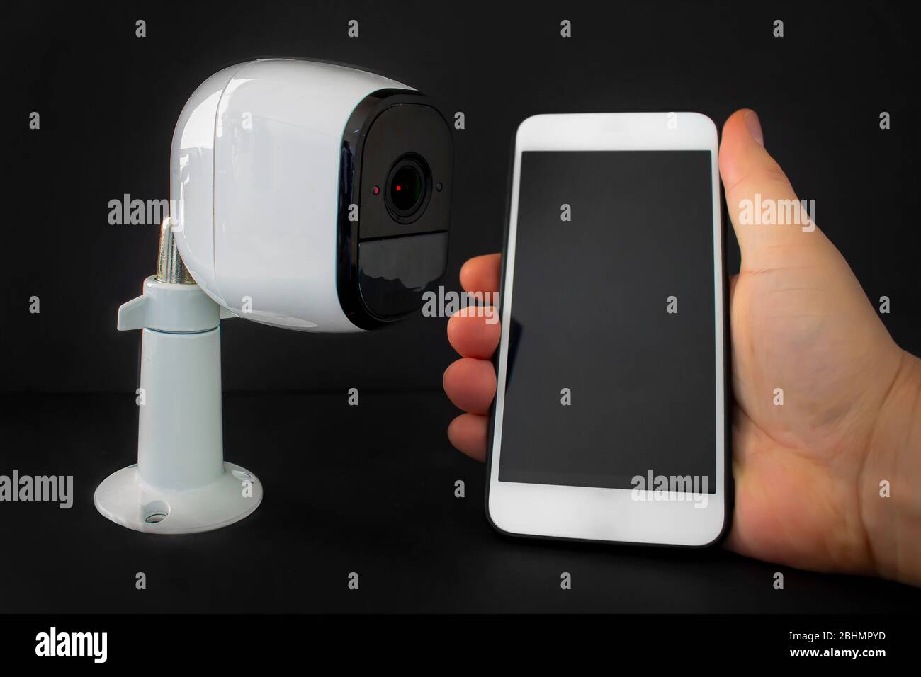 Una videocamera di sicurezza intelligente con uno smartphone in attesa da una persona Foto Stock