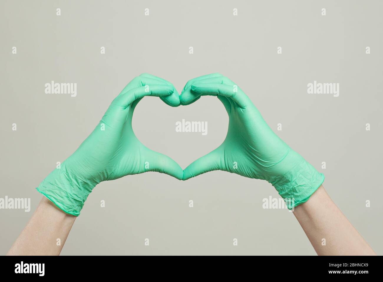 Cuore di medico guanti mani. Il cuore dalle mani in guanti medici su sfondo bianco Foto Stock