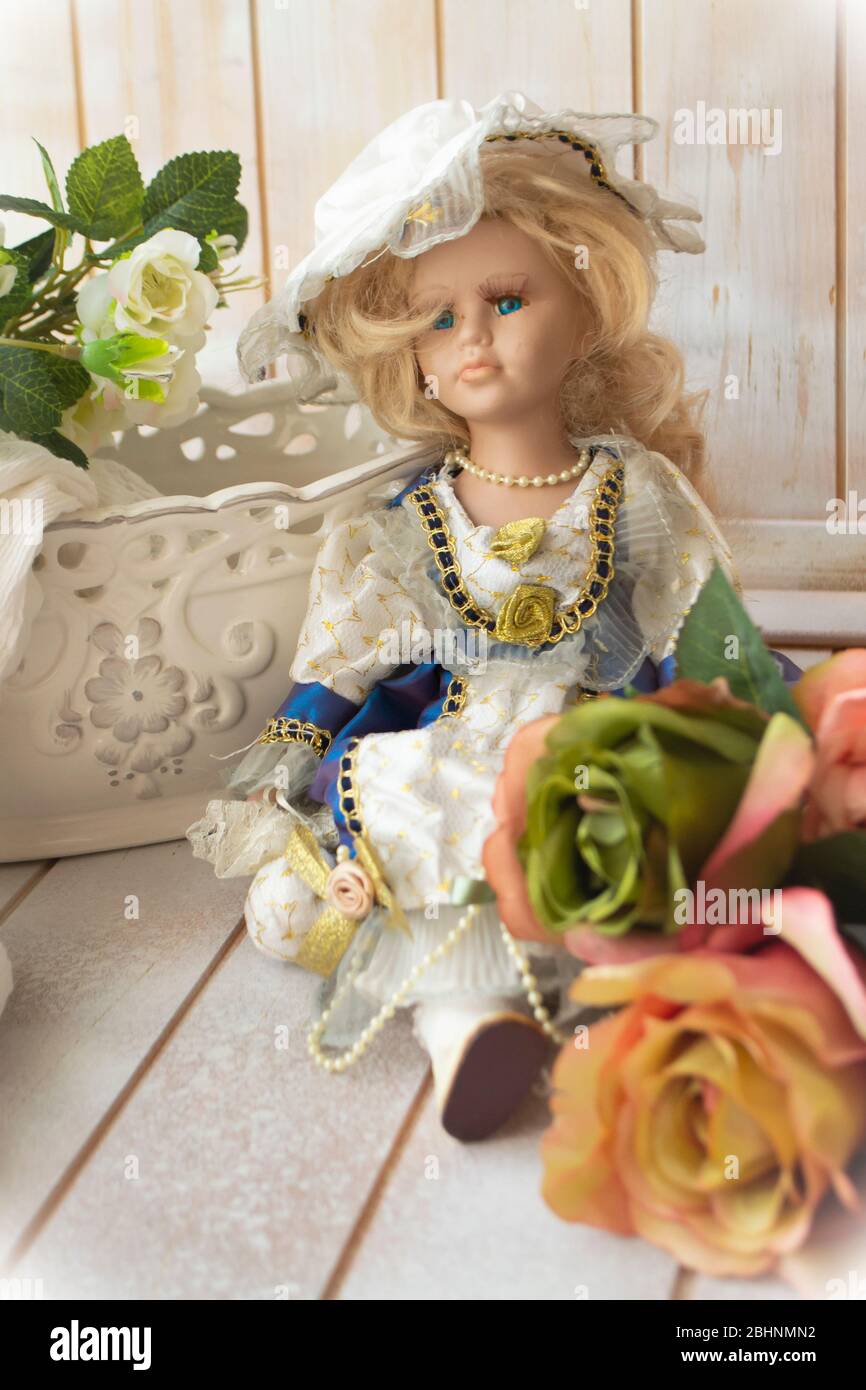 Bambola in porcellana antica in stile vittoriano. Bambola con abiti e rose pastello. Immagine verticale, sfondo shabby Foto Stock