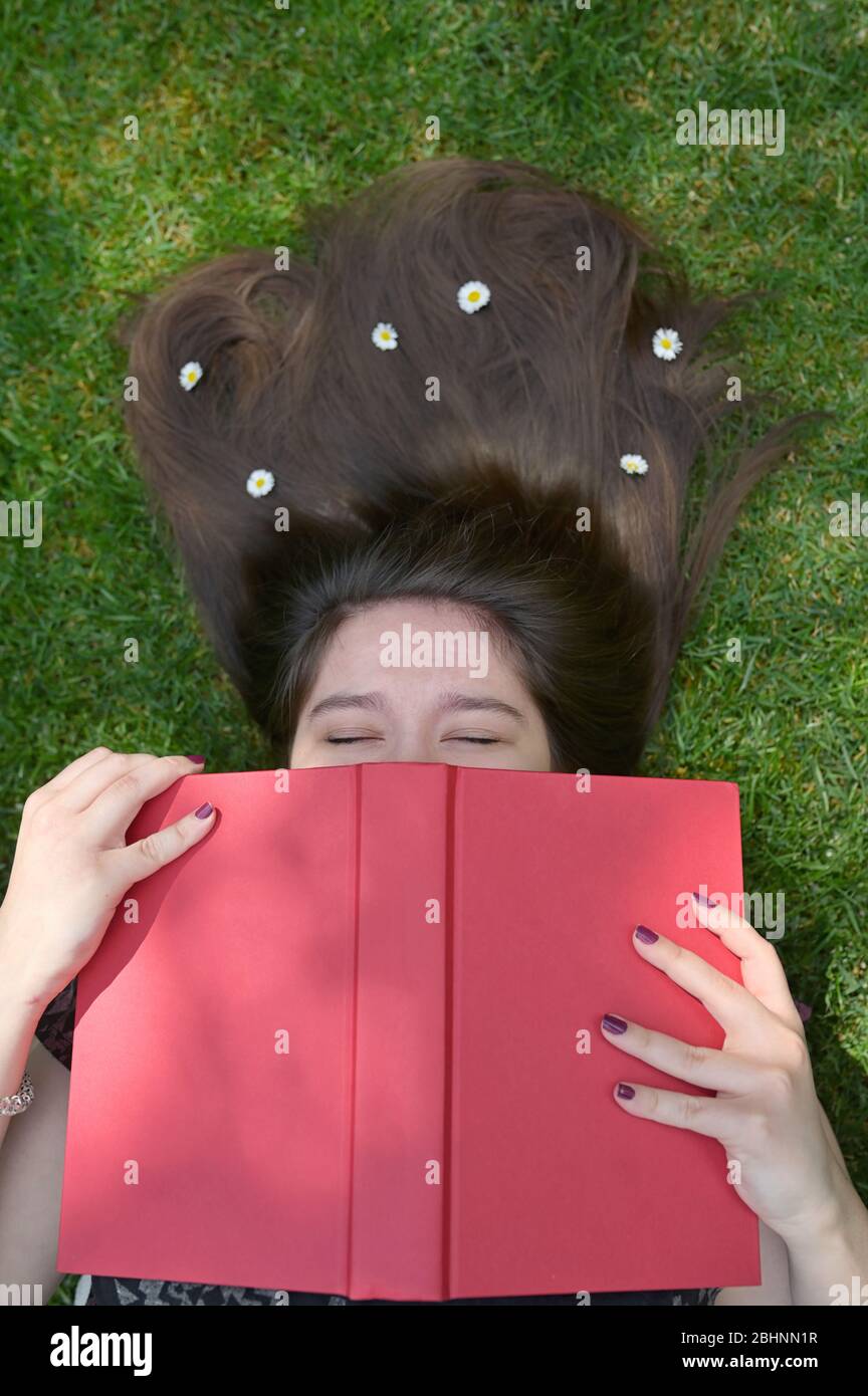 Concetto ragazza che giace in erba e lettura Libro Foto Stock