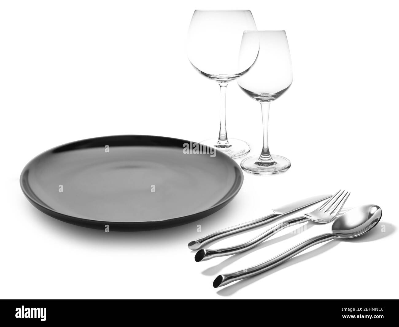 Piatto nero con forchetta e coltello da vino bicchieri isolati Foto Stock