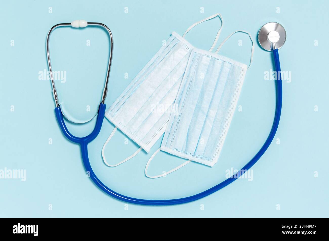 Protezione da coronavirus. Stetoscopio e maschere chirurgiche mediche su sfondo blu. Malattie respiratorie infettive. Misure igieniche per prevenire la diffusione Foto Stock