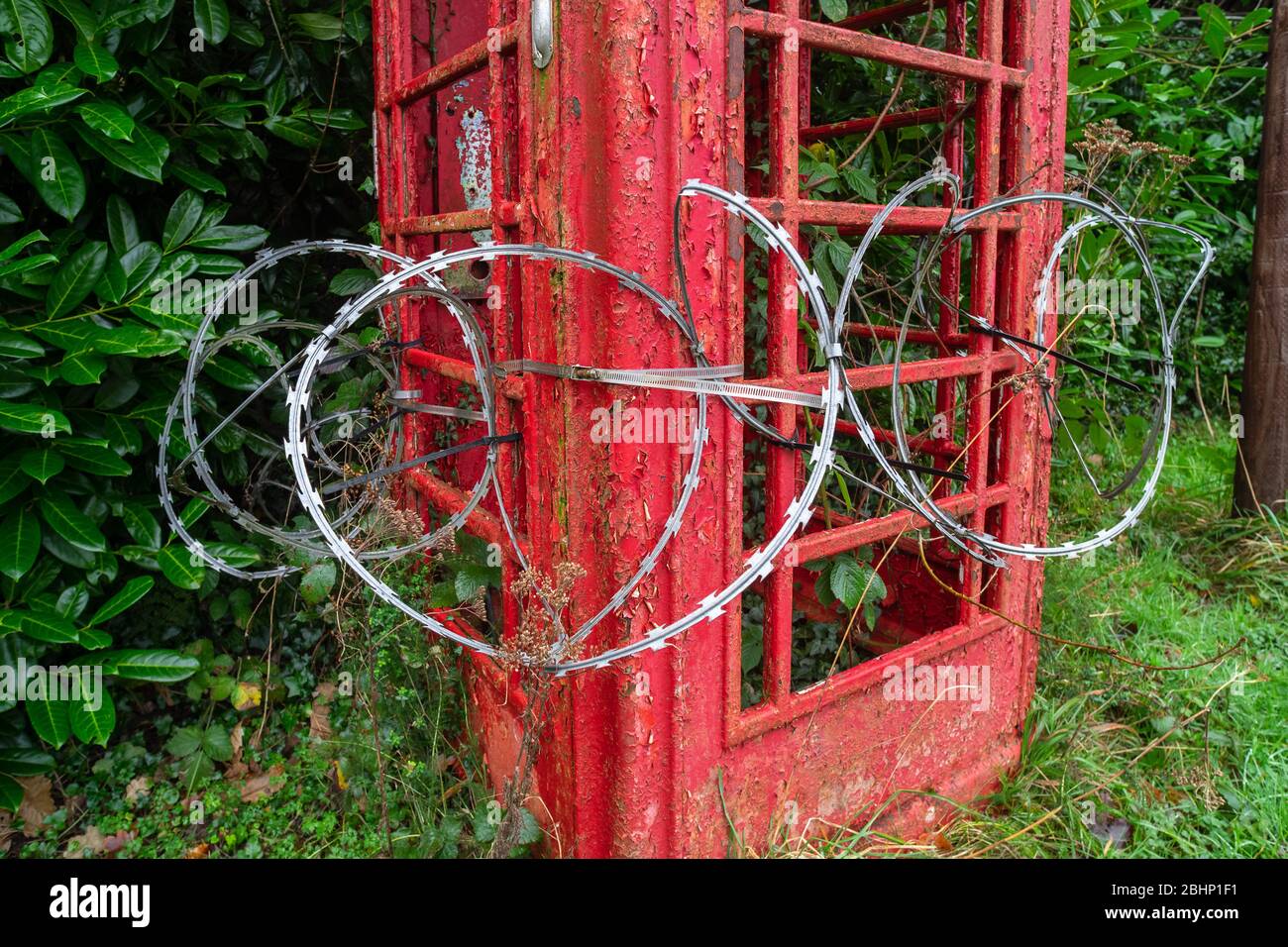 Rubrica tradizionale inglese rossa, derelict e circondato da filo rasoio Foto Stock