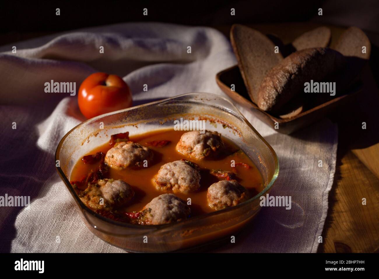 Polpette in salsa di pomodoro in un piatto di vetro, pane di segale, tovaglia di lino, tasto basso Foto Stock