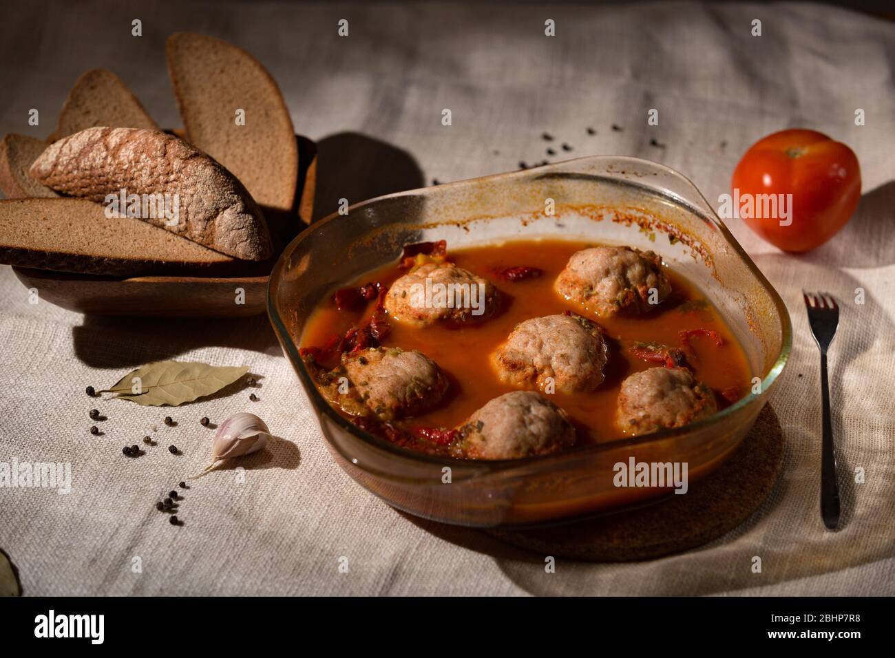 Polpette in salsa di pomodoro in un piatto di vetro, pane di segale, tovaglia di lino, tasto basso Foto Stock