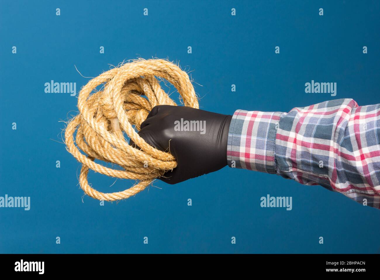 Corda gialla nella mano esperta di un adulto con protezione. Corda spessa per legare oggetti. Foto Stock