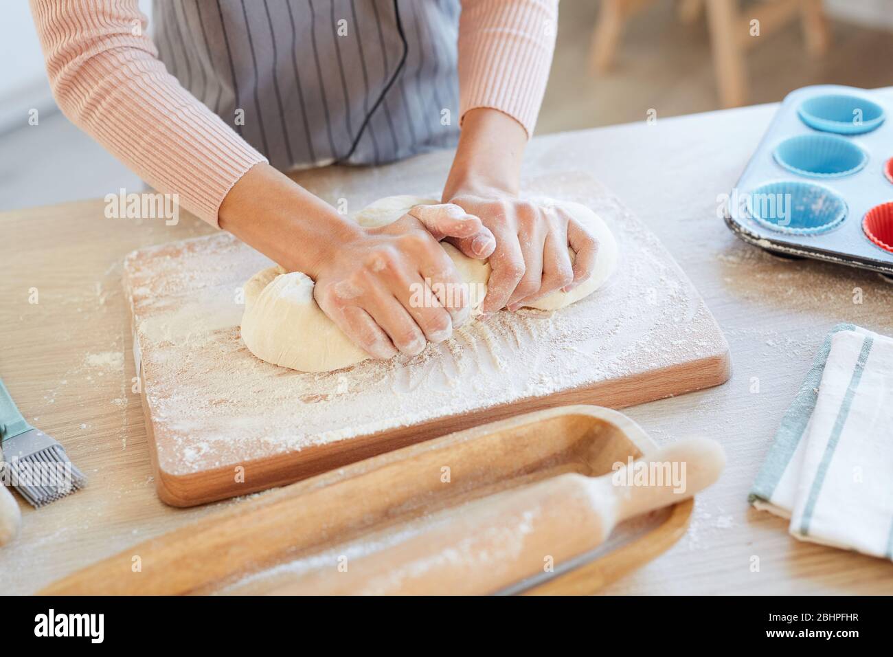 High angle orizzontale shot di mani femminili impastare pasta da forno su piano di cucina in legno per cupcake Foto Stock