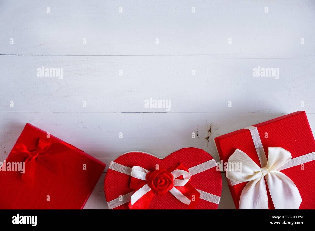 Scatole regalo rosse su sfondo bianco di legno. Concetto di storie d'amore e per San Valentino. Foto Stock