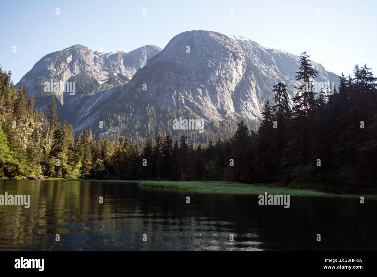 Un estuario del fiume sotto le montagne di granito alla confluenza dell'Oceano Pacifico nella Great Bear Rainforest, costa settentrionale, British Columbia, Canada. Foto Stock