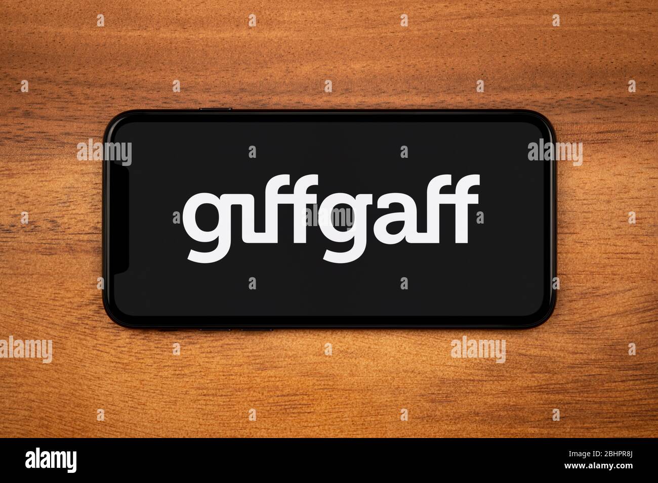 Uno smartphone con il logo Giffgaff poggia su un tavolo di legno (solo per uso editoriale). Foto Stock