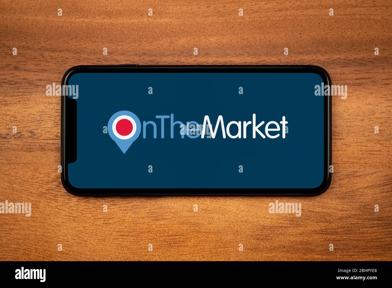 Uno smartphone con il logo OnTheMarket si trova su un tavolo di legno (solo per uso editoriale). Foto Stock