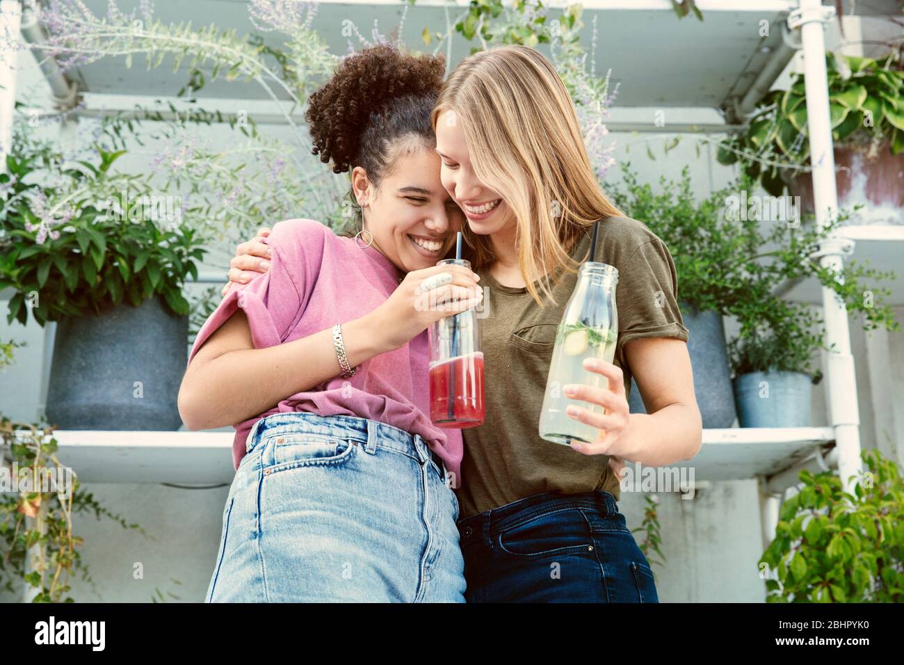 Due donne che si trovano in piedi insieme a bere un drink sulla terrazza Foto Stock