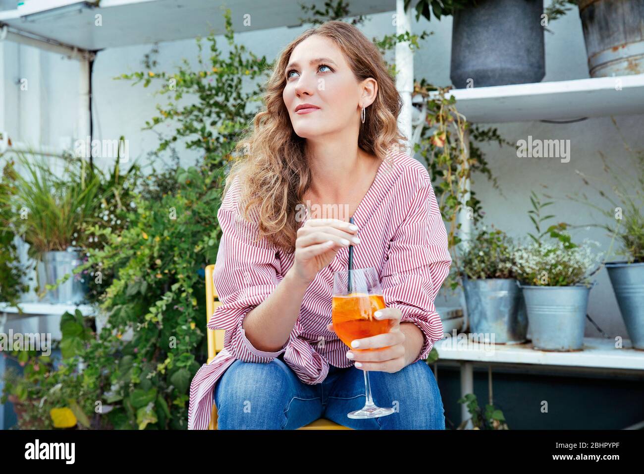 Una donna seduta su una terrazza per bere un drink Foto Stock