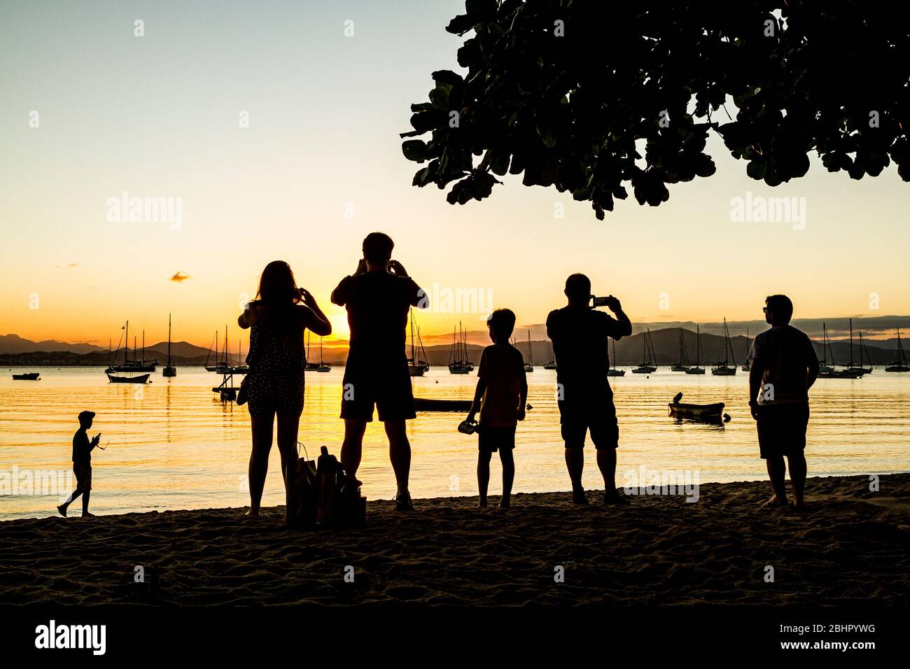 Silhouette di persone che fotografano il tramonto sulla spiaggia di Santo Antonio de Lisboa. Florianopolis, Santa Catarina, Brasile. Foto Stock