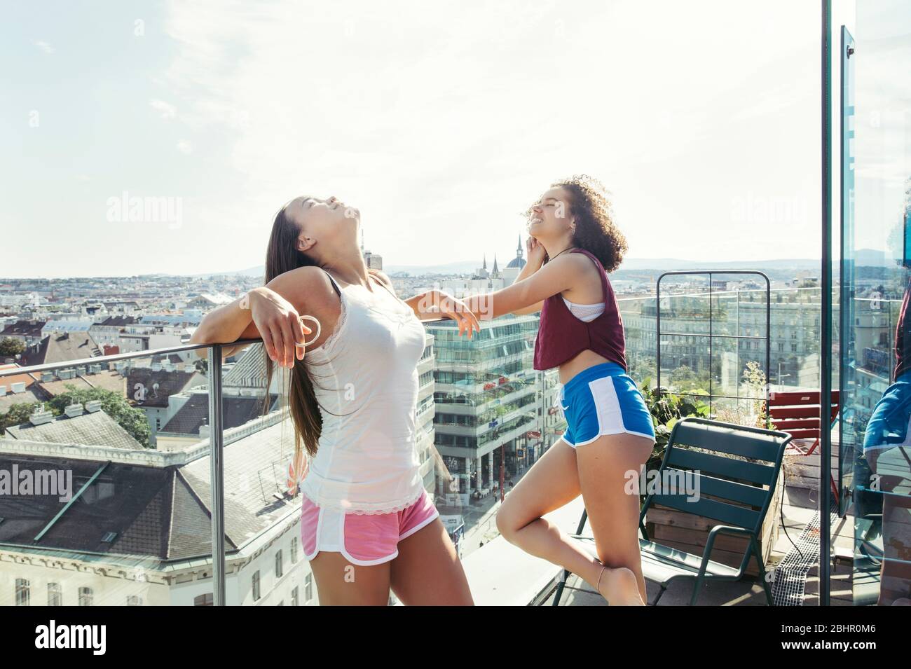 Due donne che indossano pantaloncini e camicie da giubbotto in piedi su un balcone che si affaccia su Vienna. Foto Stock