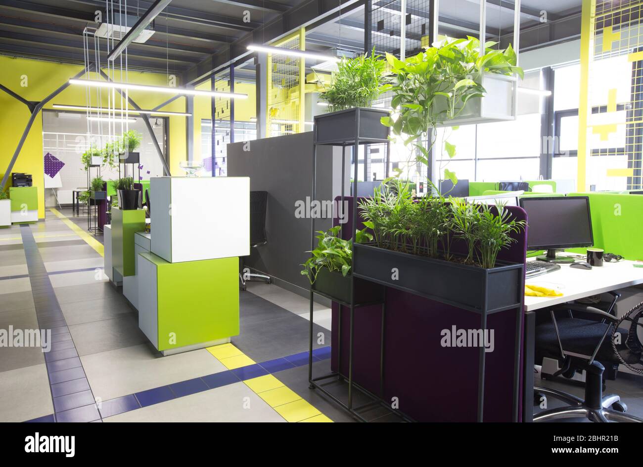 Spazio aperto interno con piante verdi e posti per lavoratori Foto Stock
