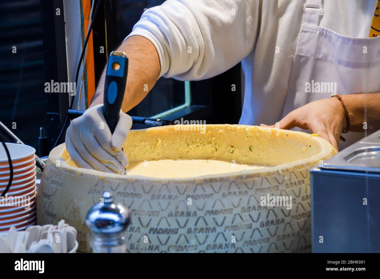 Mano con spatola una ruota di parmigiano (parmigiano) Foto Stock