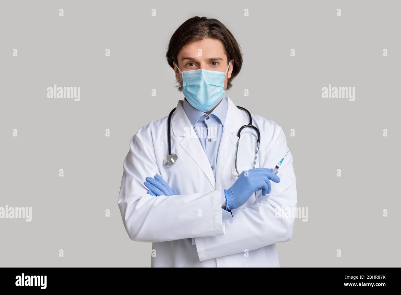 Medico di sesso maschile sicuro nella maschera medica protettiva che tiene la siringa con il vaccino Foto Stock