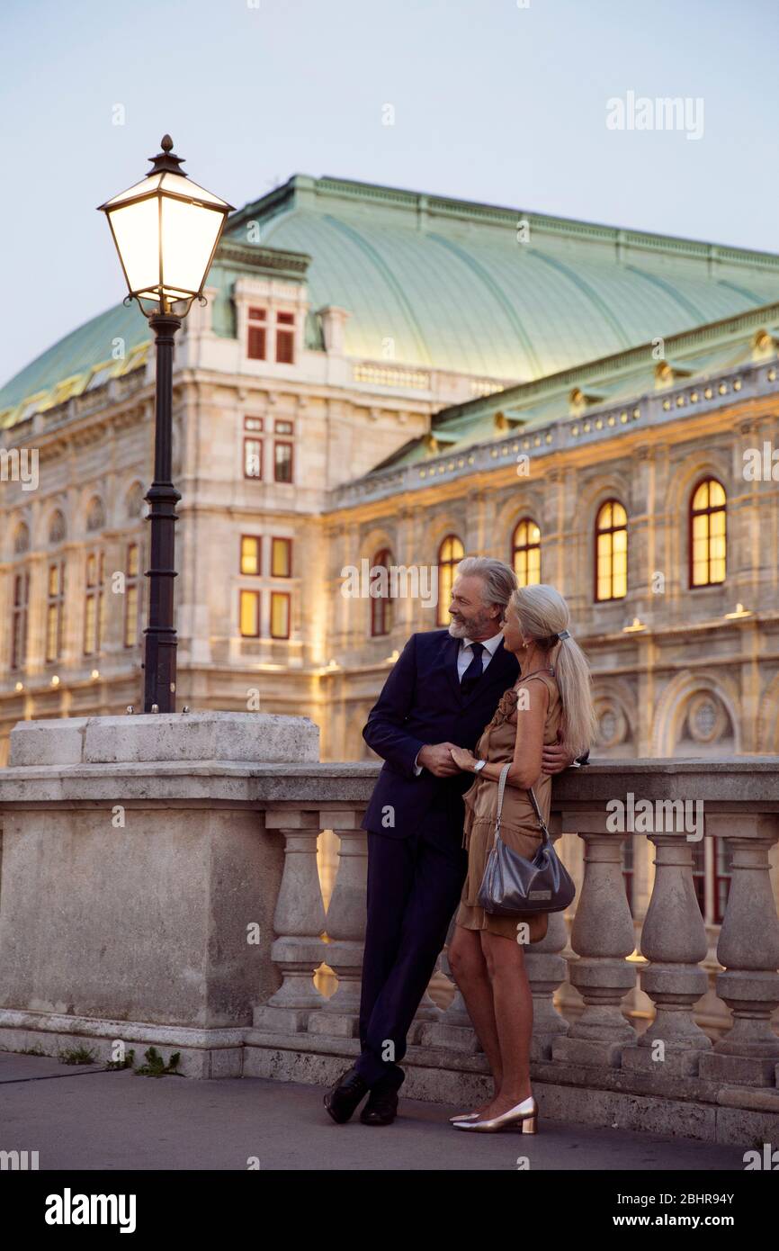 Una coppia in piedi braccio appoggiato contro una balaustra durante la prima sera a Vienna. Foto Stock