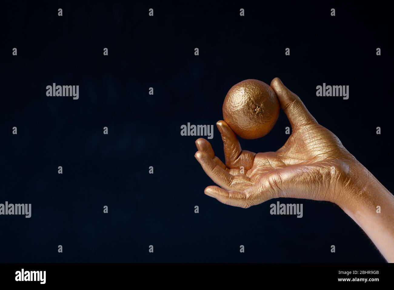 Mano cosparsa di vernice oro tiene limone Foto Stock