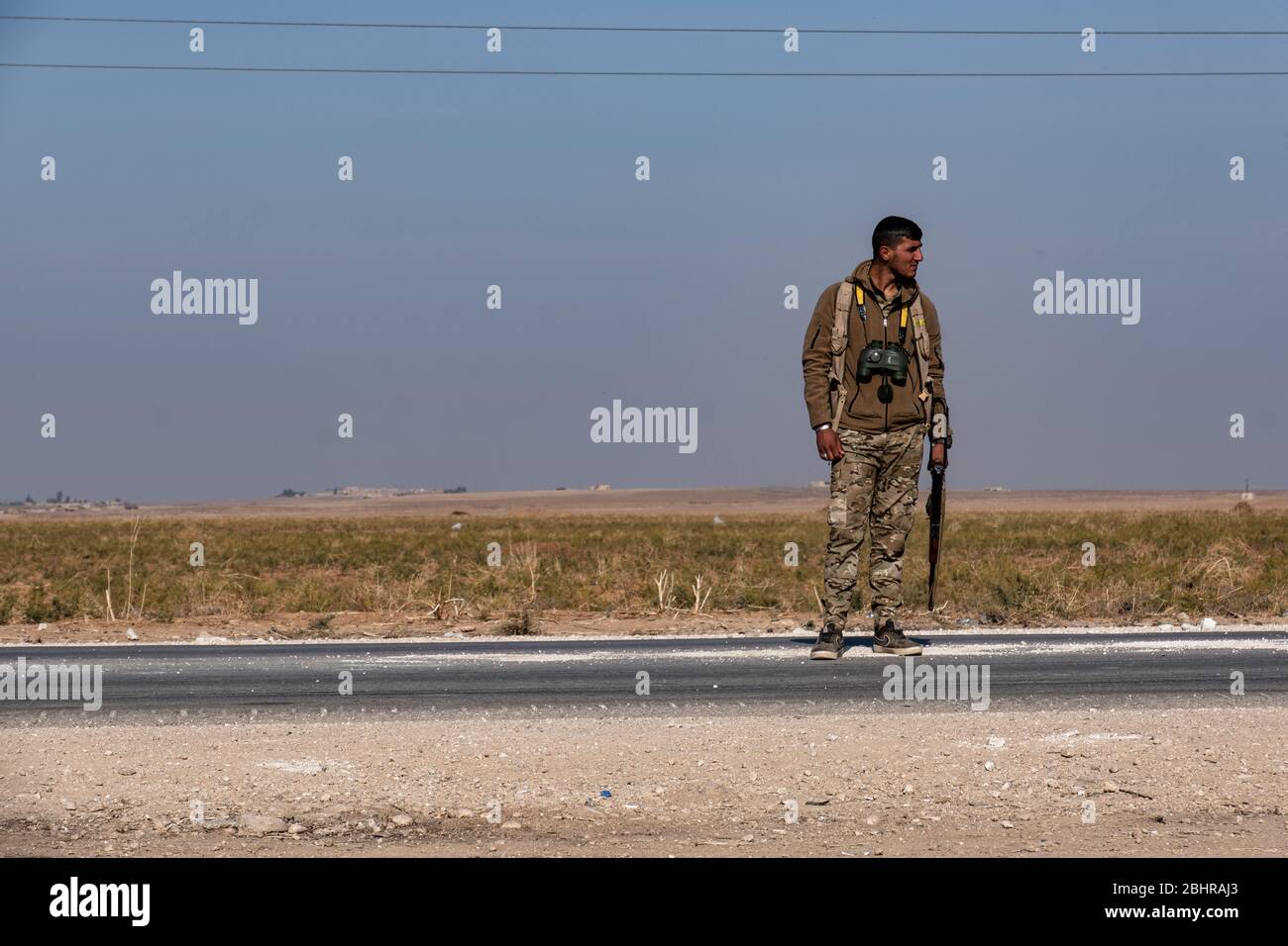 Un combattente SDF protegge la strada tra tal Tamr e le linee di fronte con i combattenti turchi a Hasakah, in Siria. Foto Stock