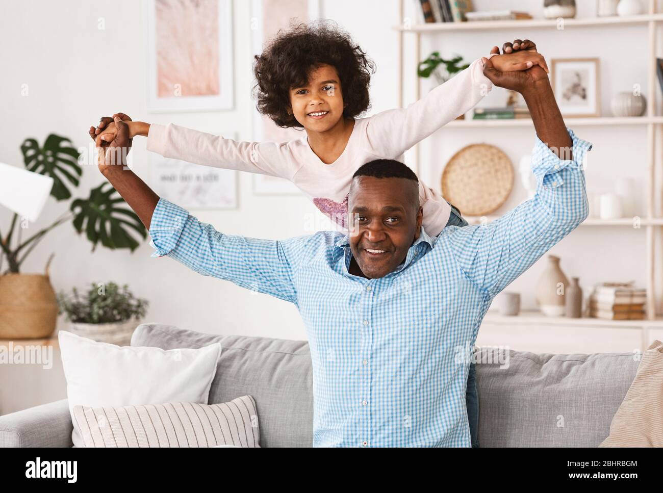 Giocate con il nonno. Uomo africano americano maturo che gioca gioco divertente con la nipote a casa Foto Stock