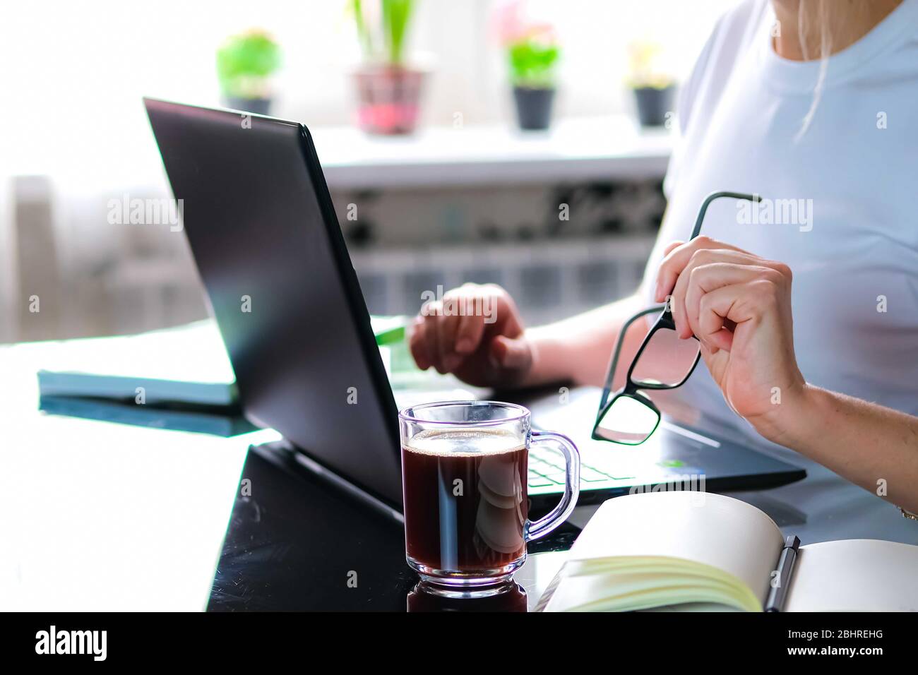 Immagine ritagliata di una ragazza o di una donna che lavora sulla quarantena da casa sulla cucina che indossa pijama.Home ufficio o concetto di apprendimento a distanza. Freelance o e-learning. Foto Stock