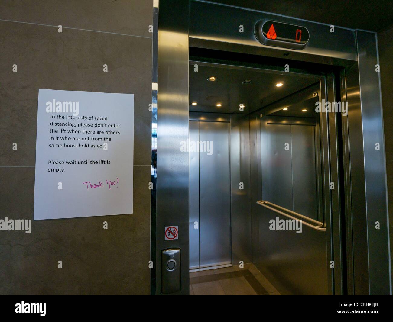 Avviso circa le distanze sociali sulla porta ascensore in blocco di appartamenti, Edimburgo, Scozia, Regno Unito Foto Stock