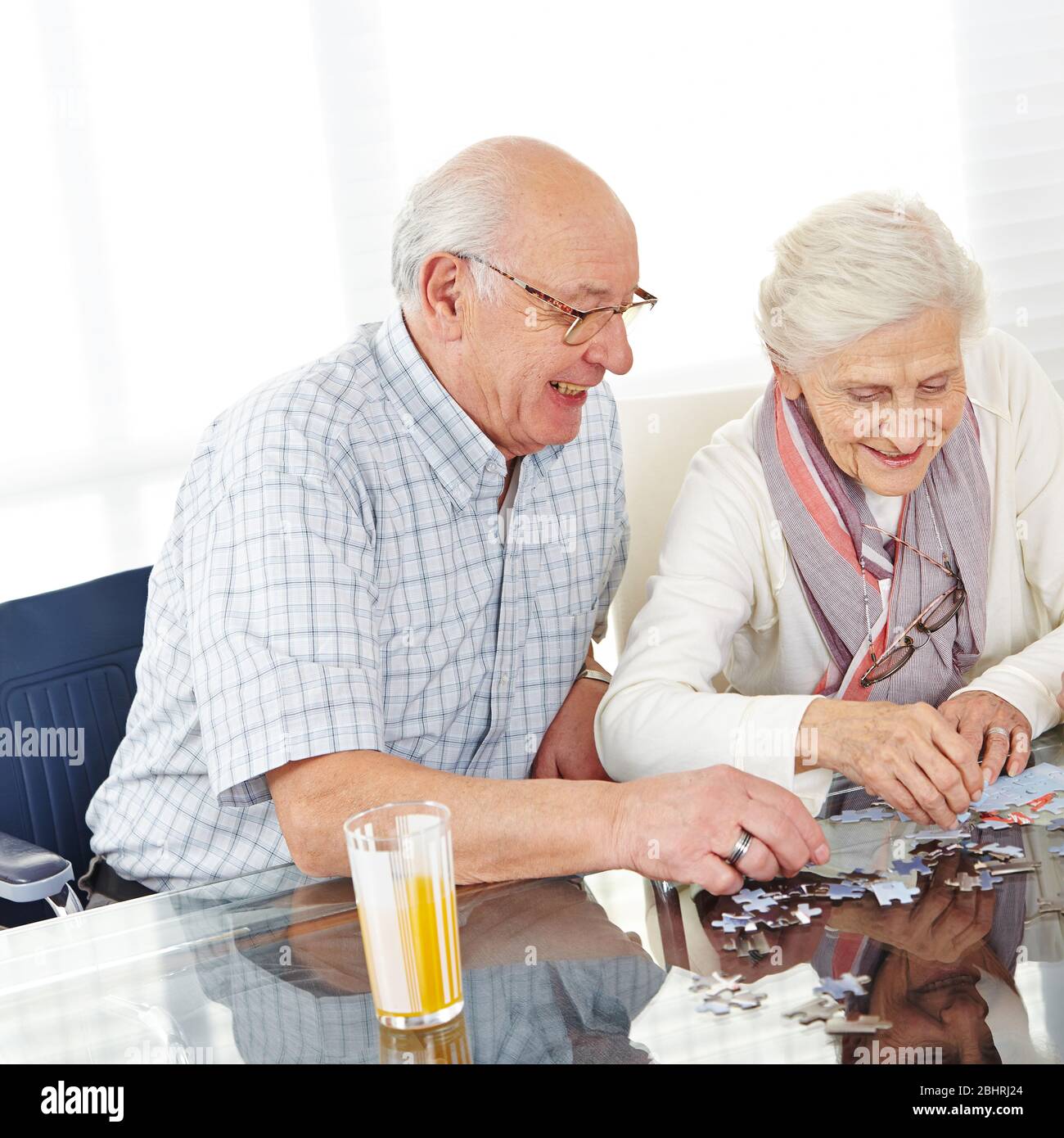 Una coppia felice di anziani risolvere insieme puzzle come formazione di memoria Foto Stock