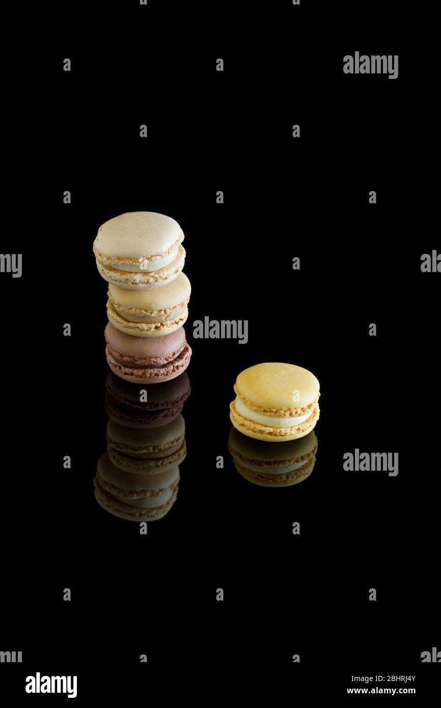 Macaron colorati con riflessione isolata su sfondo nero. Dolci francesi. Foto Stock