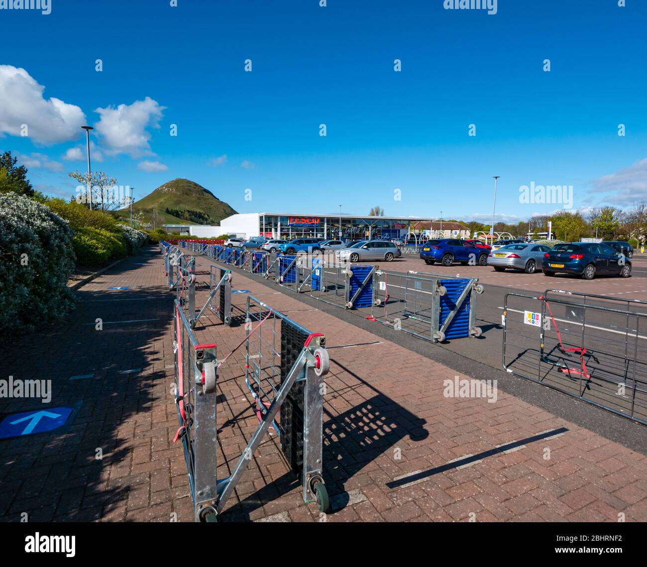 Barriere realizzate da carrelli nel parcheggio del supermercato Tesco per creare barriere sociali sicure per gli acquirenti in coda, North Berwick, Scotland, UK Foto Stock