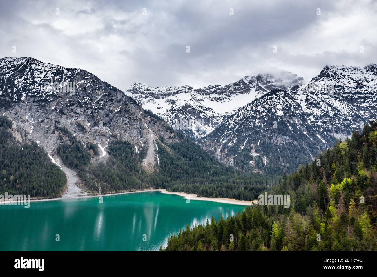 L'improbabile paesaggio aereo del lago, Italia, drone vola basso su acque azzurre del lago, una spiaggia vuota, tempo nuvoloso, costa, ponte Foto Stock