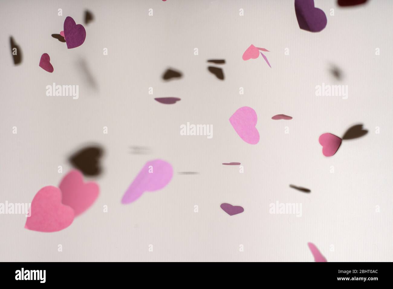 Cuori di carta viola e rosa volanti, sfondo per San Valentino, biglietto di auguri per il compleanno, concetto di amore Foto Stock