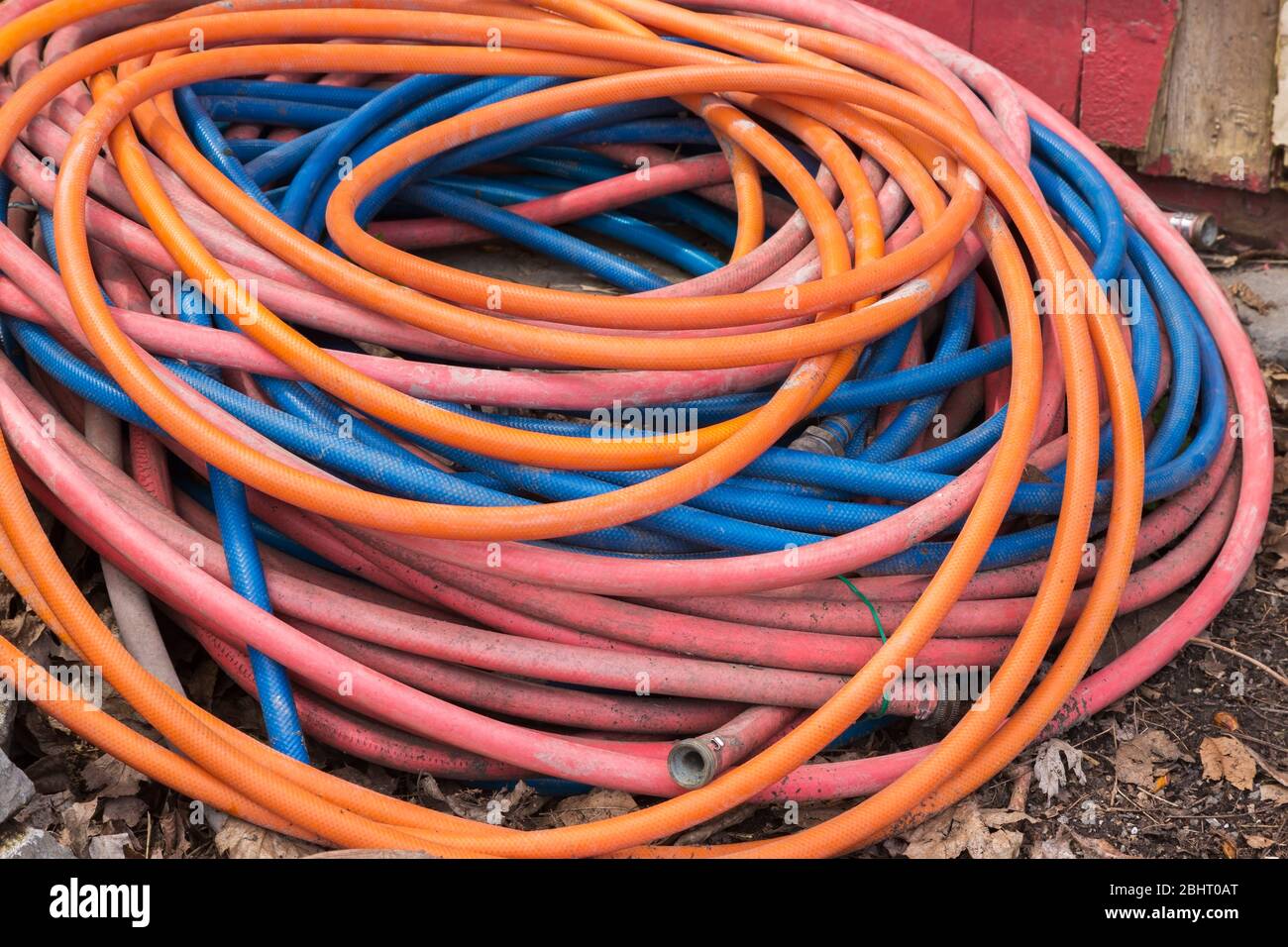 Tubo flessibile di irrigazione per giardino a serpentina rosso, blu e arancione a serpentina Foto Stock