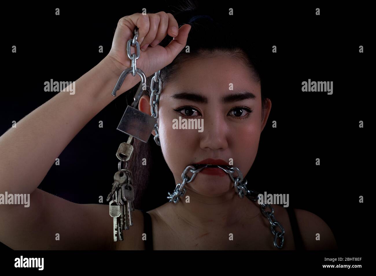 Ritratto giovane Asia donna coperto bocca da una catena di acciaio e sbloccare per proibirgli il libero speeching a sfondo nero, Shut up o stop talki Foto Stock
