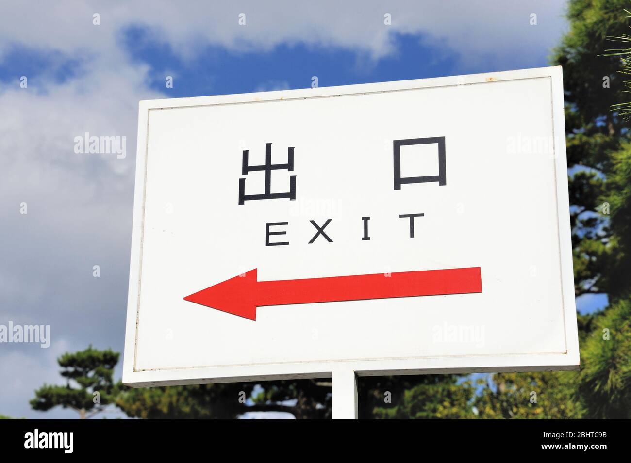 Segno con una freccia rossa rivolta verso sinistra e la parola uscita in inglese e in giapponese Kanji script i simboli per uscire e bocca Foto Stock