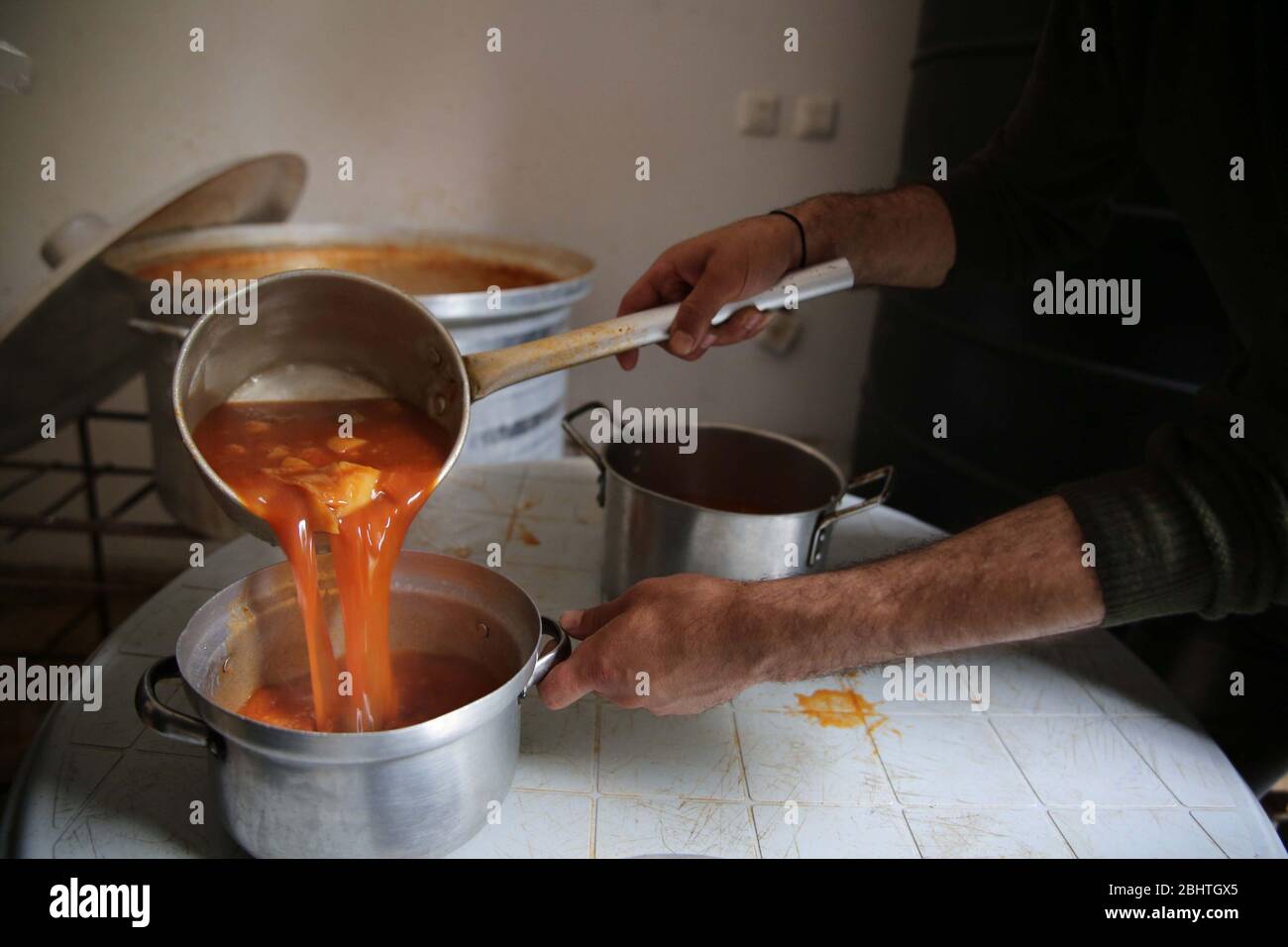 Al-Nuseirat campo profughi, striscia di Gaza, Palestina. 27 aprile 2020. Donne palestinesi cucinano e distribuiscono Iftar Measl per le famiglie povere al campo profughi di al-Nuseirat nel centro della striscia di Gaza. Credit: Hassan Jedi/Quds Net News/ZUMA Wire/Alamy Live News Foto Stock