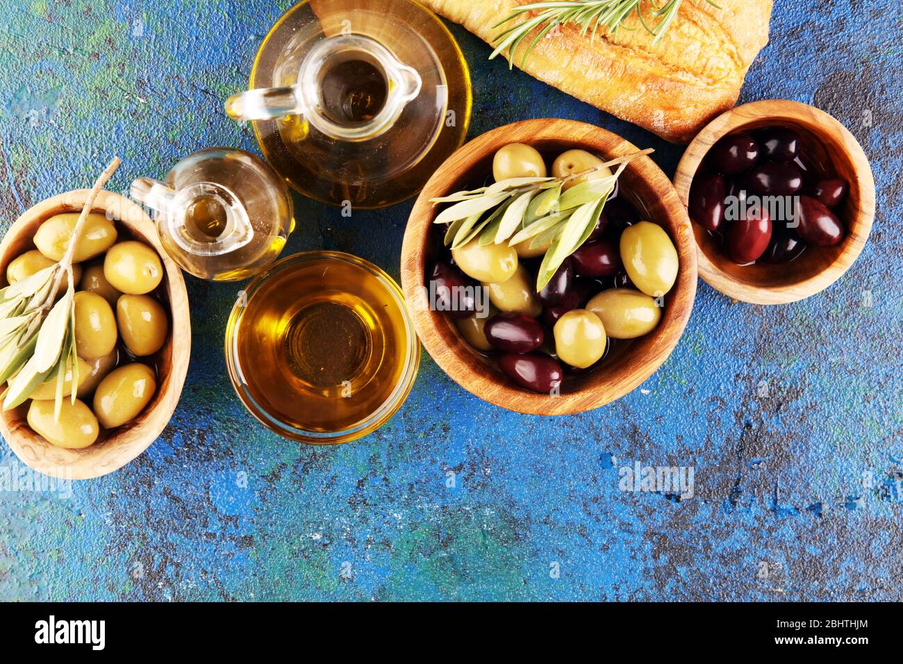 Bottiglia olio d'oliva vergine e di olio in una ciotola con alcune olive. Foto Stock