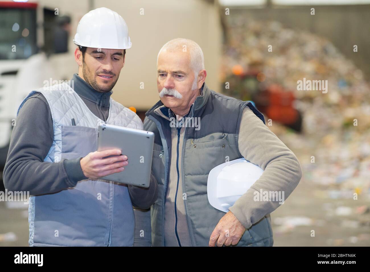 lavoratori anziani e giovani che lavorano con un tablet in fabbrica Foto Stock