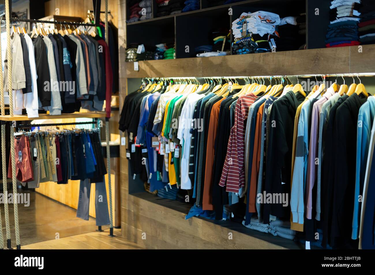 Negozio di abbigliamento uomo, varietà di abiti casual su appendiabiti e  mensole in negozio di abbigliamento Foto stock - Alamy