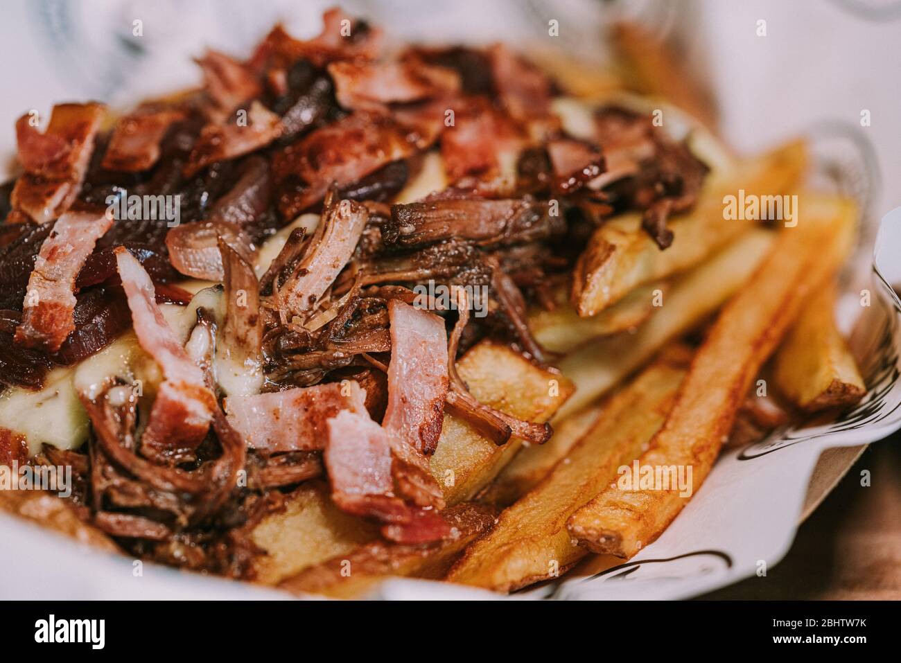 Carne tritata con pancetta tritata e saltata accompagnata da cipolla rossa saltati e patatine fritte Foto Stock