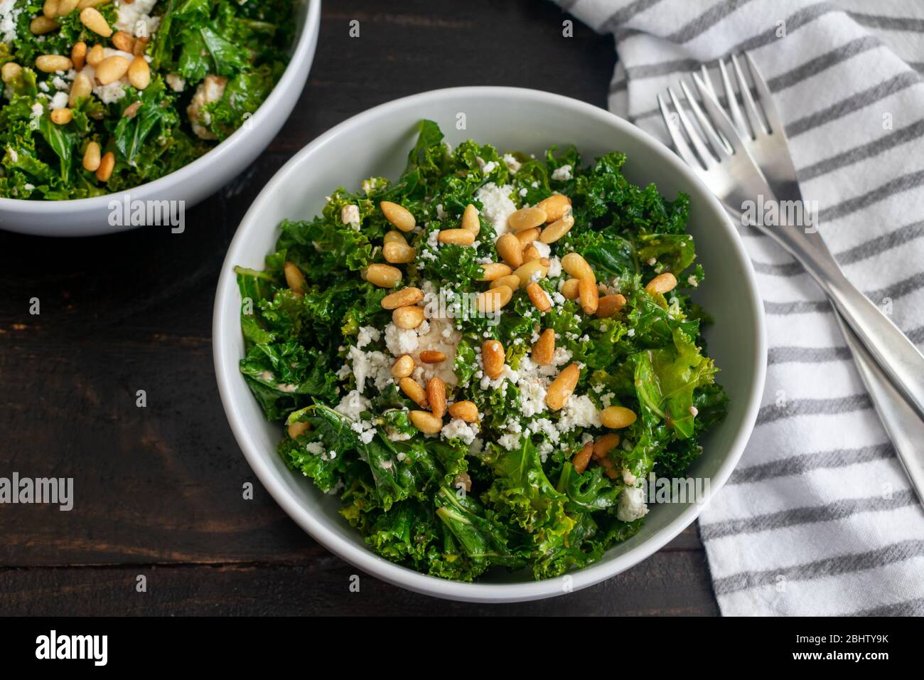 Insalata di Kale con condimento alla cipolla dolce: Insalata di Kale con condimento alla cipolla dolce condito con formaggio di capra sbriciolato e pinoli tostati Foto Stock