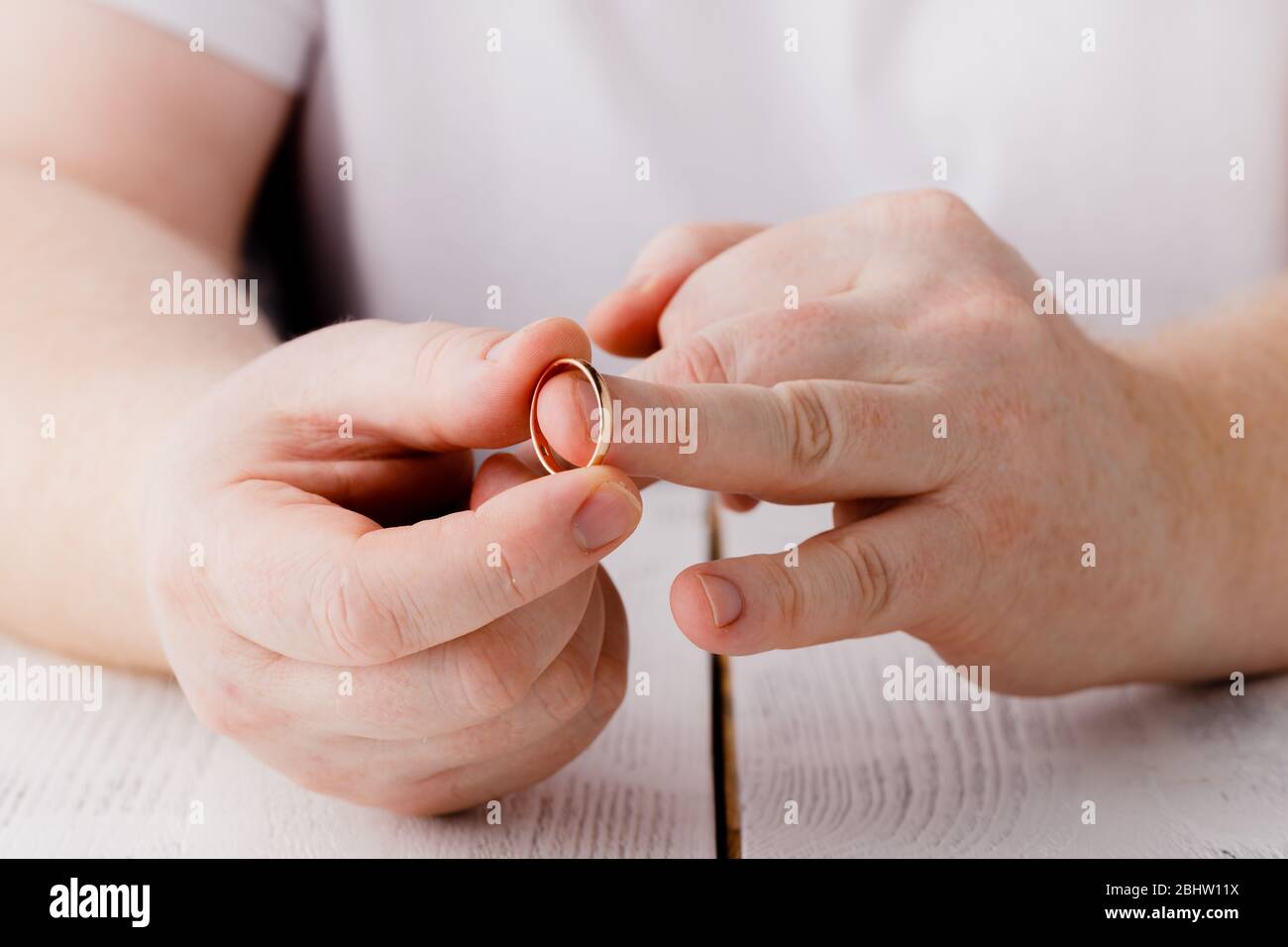 Uomo firma decreto di divorzio e decollo di nozze anello, copia spazio, sfondo sfocato Foto Stock