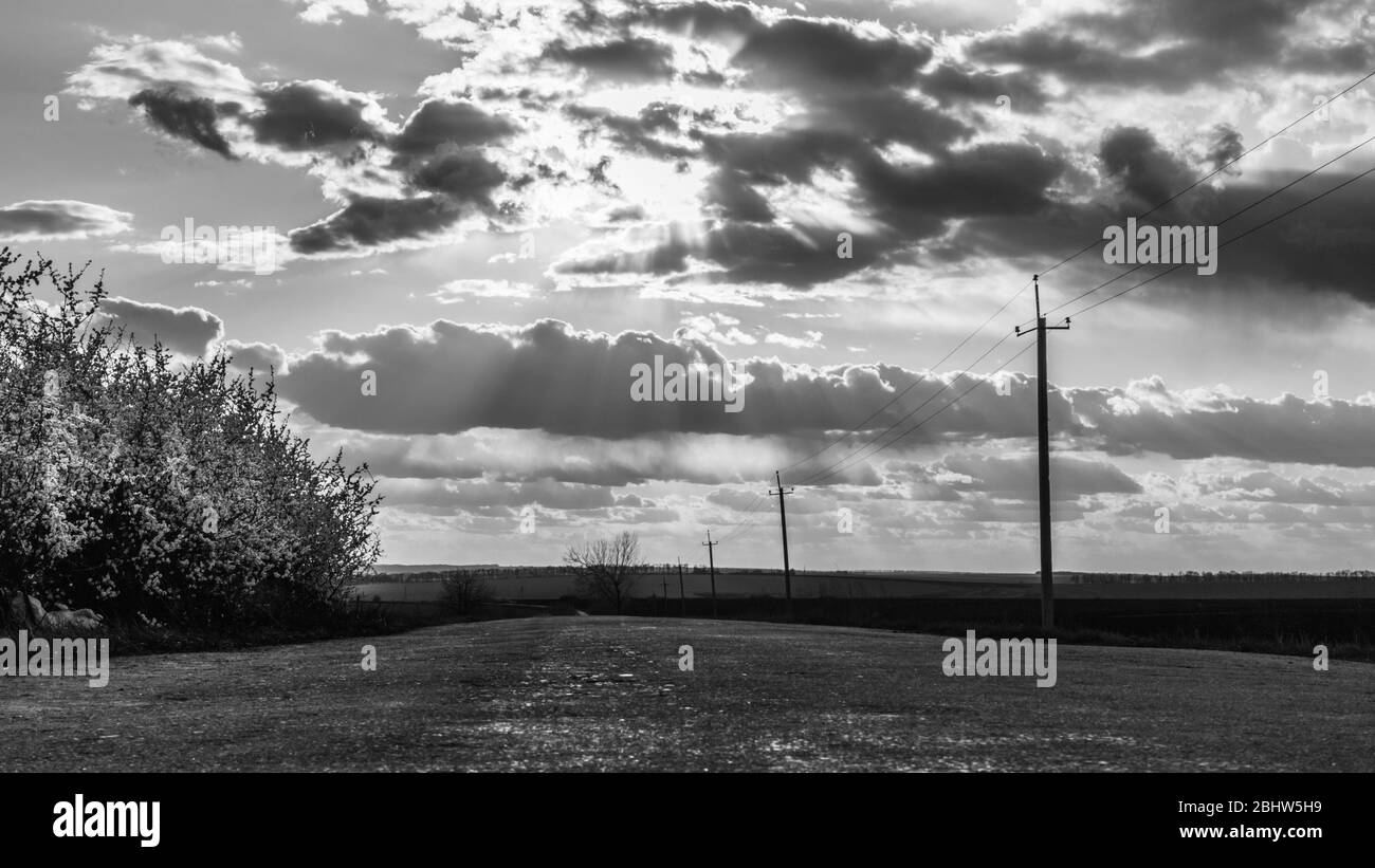 Epico Moody scuro scala di grigi luce primavera tempo campi di campagna con cielo nuvoloso drammatico e raggi del sole Foto Stock